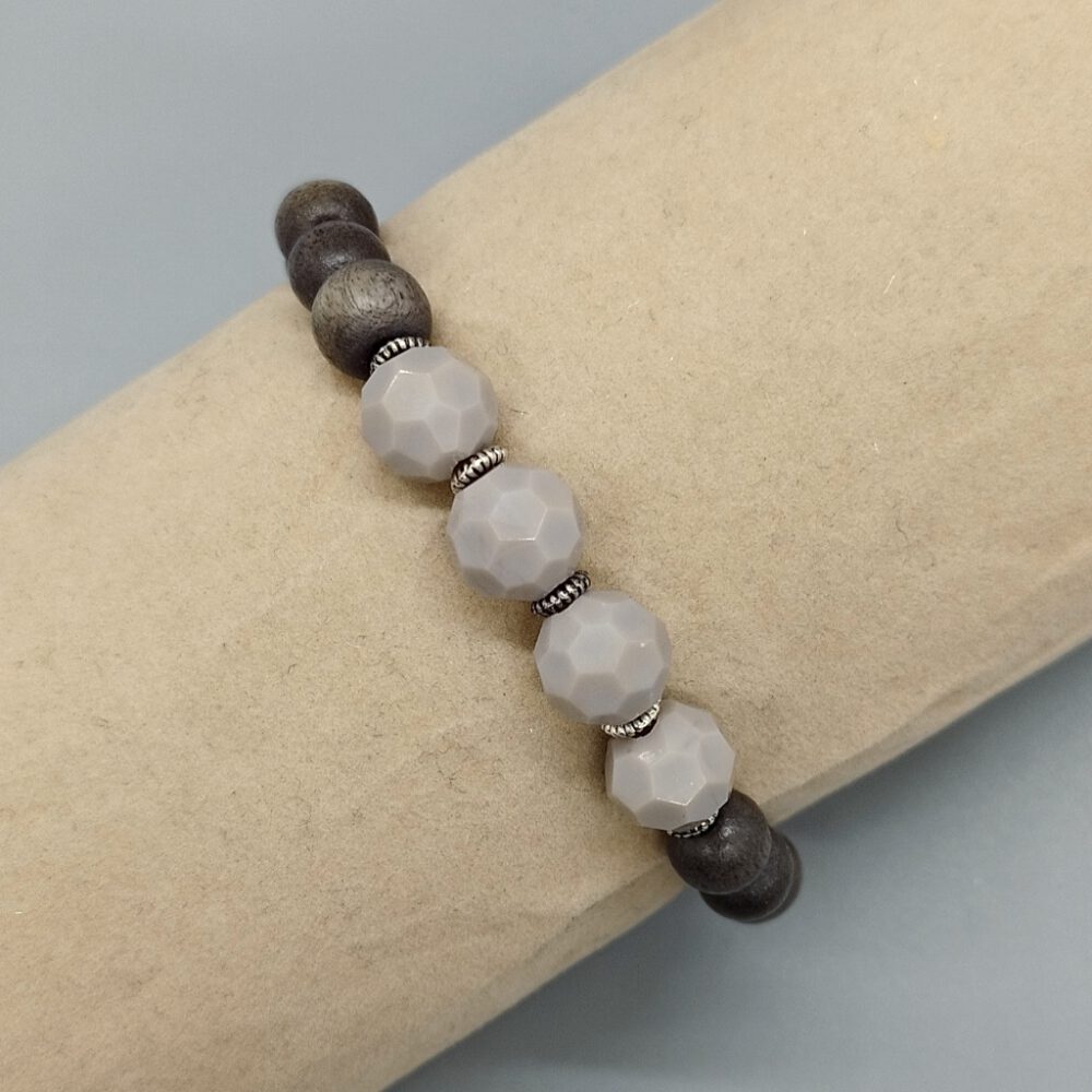 Das Armband am Model präsentiert die perfekte Passform und den harmonischen Farbverlauf. Armband Holzperlen + Kristalle grau-nude