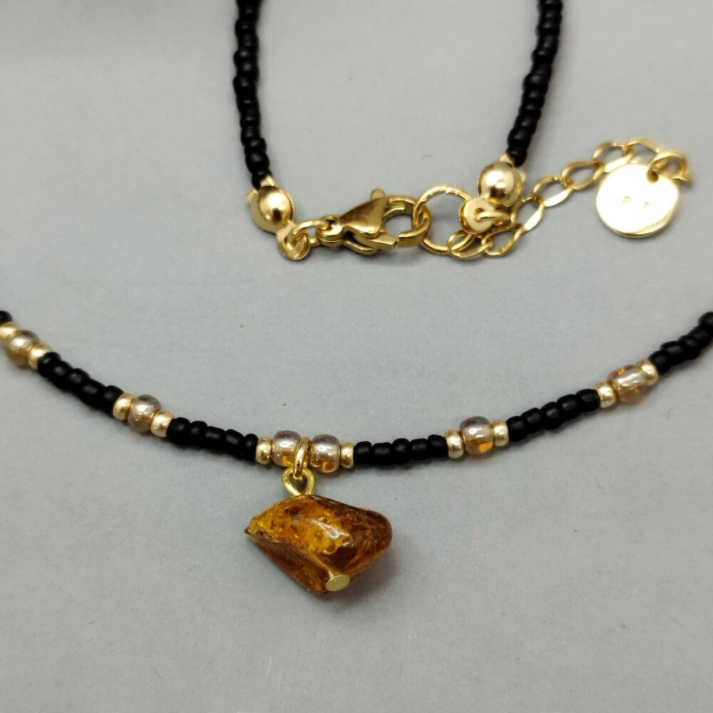 Detailansicht der Choker-Kette mit Fokus auf den Bernstein-Anhänger. Kette schwarz gold mit Bernstein Anhänger