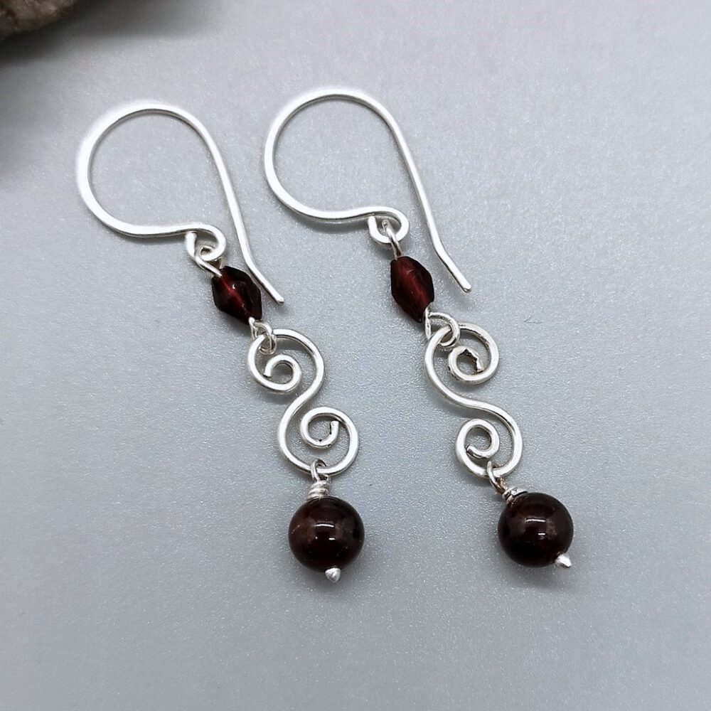 Detailansicht der Doppelspirale aus 935 Silber mit Granat und Kristall. Granat-Ohrhänger mit 935 Silber-Doppelspirale