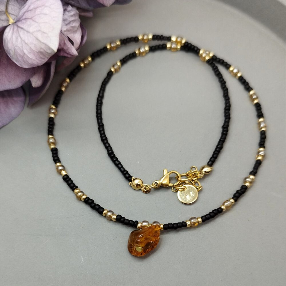 Ein Foto, das die Kette im Detail zeigt, um den Verschluss zu präsentieren. Kette schwarz gold mit Bernstein Anhänger