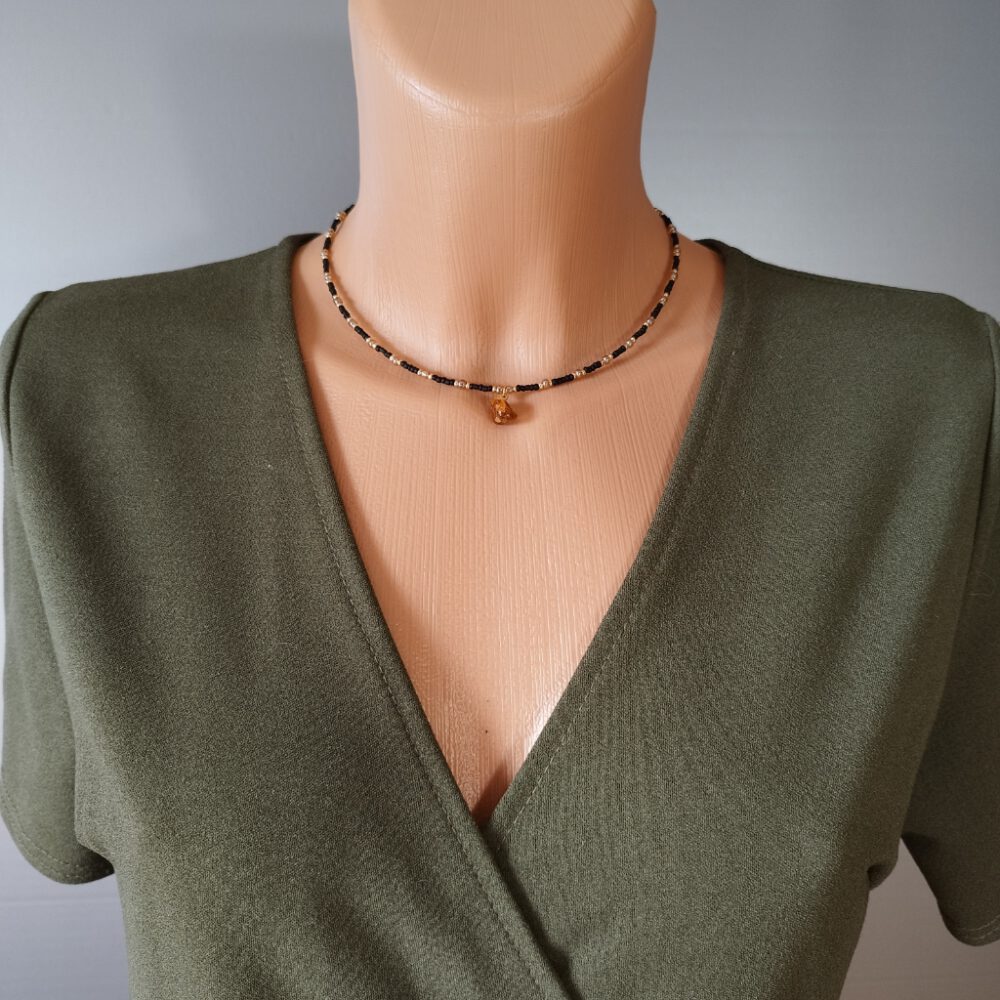 Ein Modell trägt die Choker-Kette zu einem eleganten Abendoutfit. Kette schwarz gold mit Bernstein Anhänger