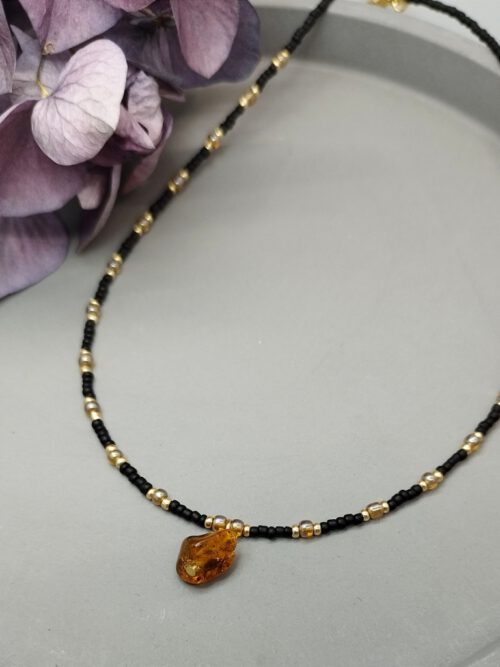 Kette aus kleinen schwarzen und goldenen Perlen mit einem Bernstein Anhänger Kette schwarz gold mit Bernstein Anhänger