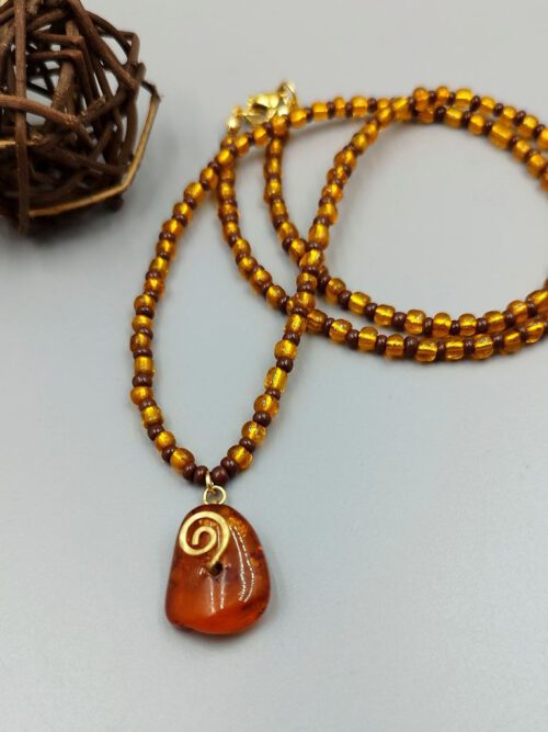 Handgefertigte Kette aus gold-braunen Rocailles mit Bernsteinanhänger und Messingspirale Kette mit Bernstein Anhänger