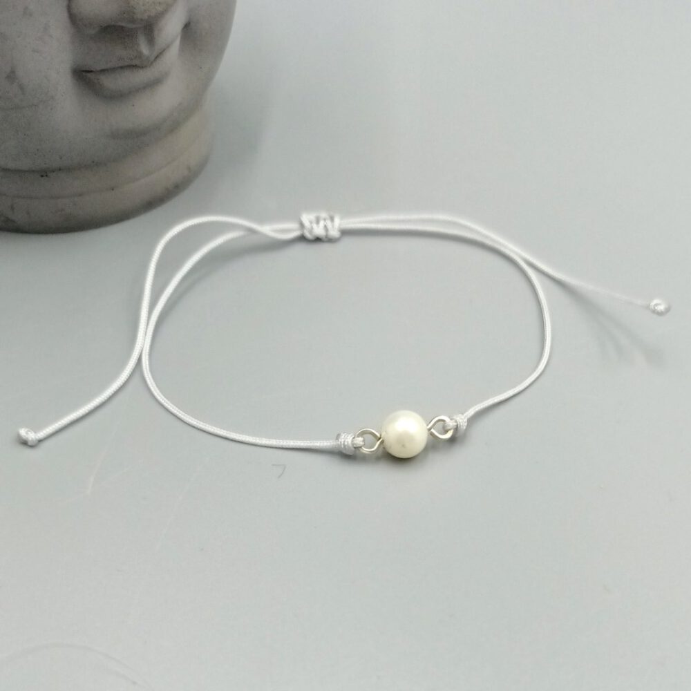 Zartes Armband mit weißer Perle auf hellgrauem Band Textilarmband mit weißer Muschelkernperle