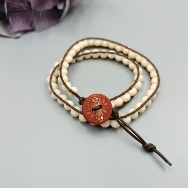 Detailaufnahme des braun gemusterten Unikat-Knopfverschlusses am Lederarmband. Leder Wickelarmband braun - creme