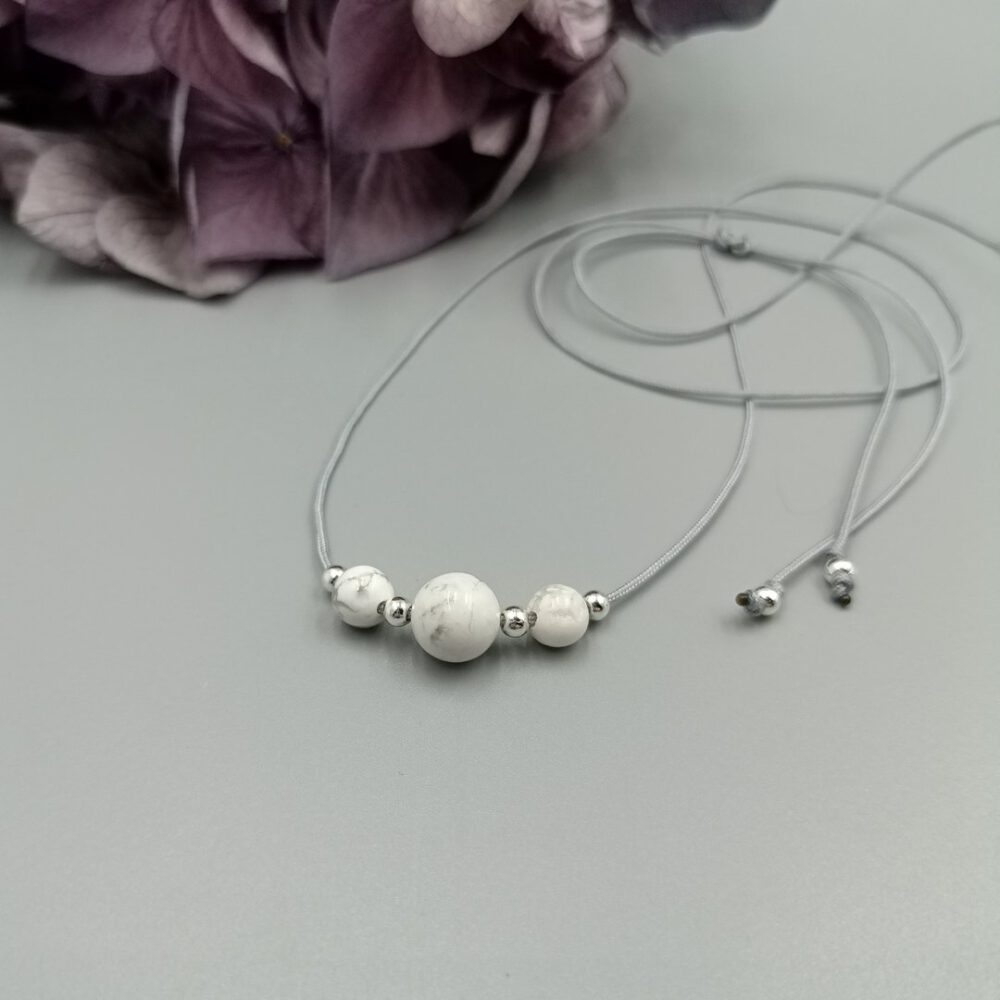Howlith Kette elegant auf grauem Hintergrund drapiert Zarte Howlith Kette in Weiß-Grau