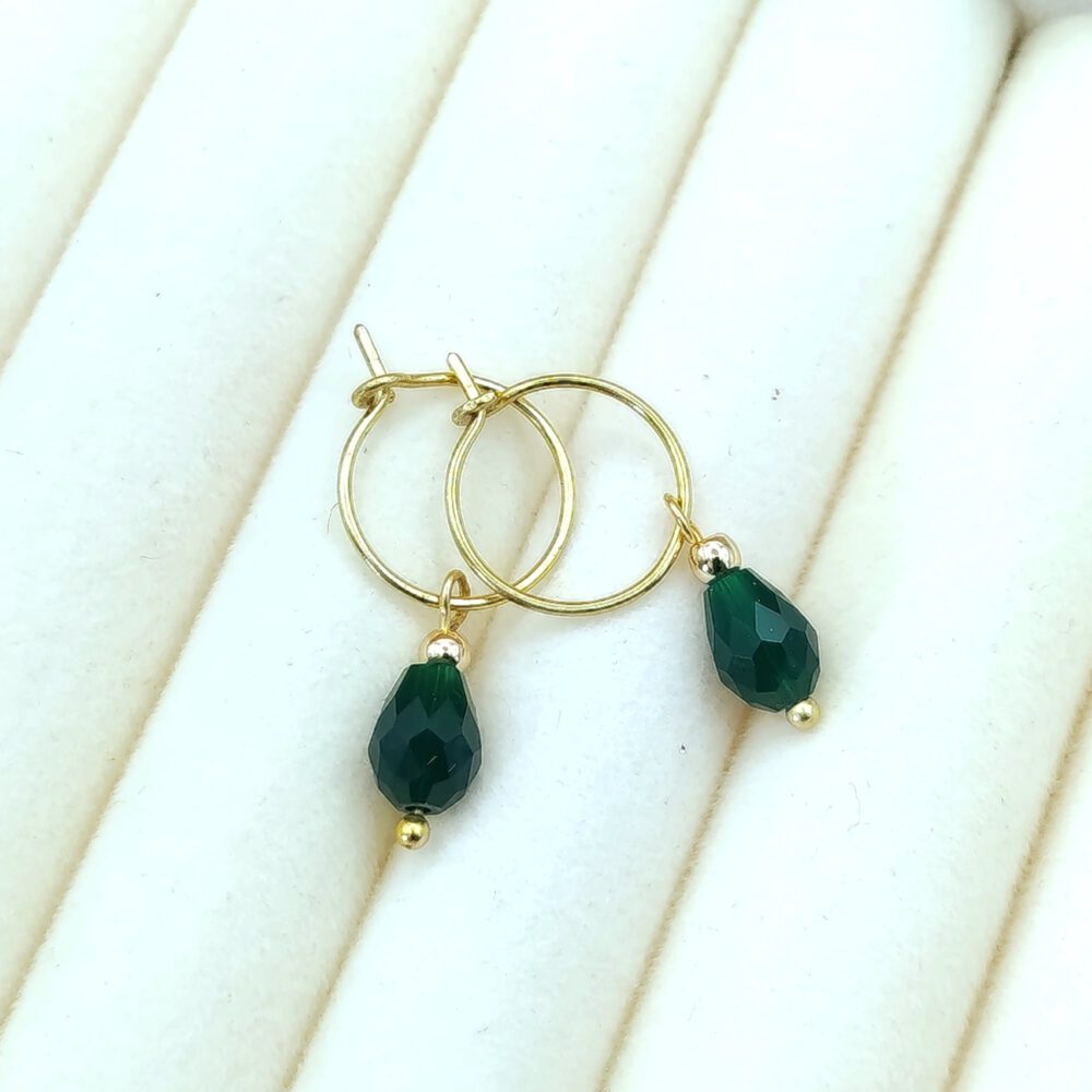 Elegante grüne Kristall-Ohrringe aus Messing neben Schmuckschatulle von CONCHA CATENA Creolen Messing mit grünem Kristall