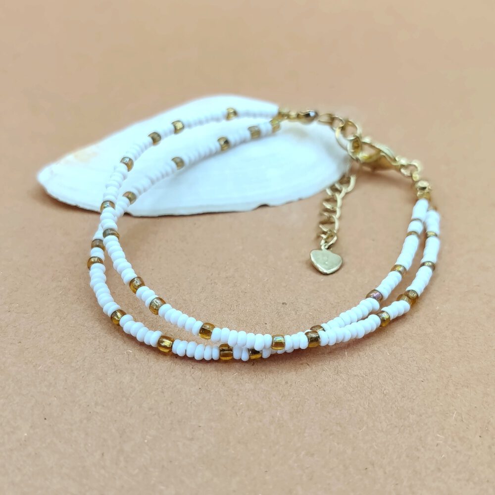 Nahaufnahme der mattweißen Perlen und goldenen Akzente des zweireihigen Armbands Zweireihiges Armband Weiß-Gold mit Herz